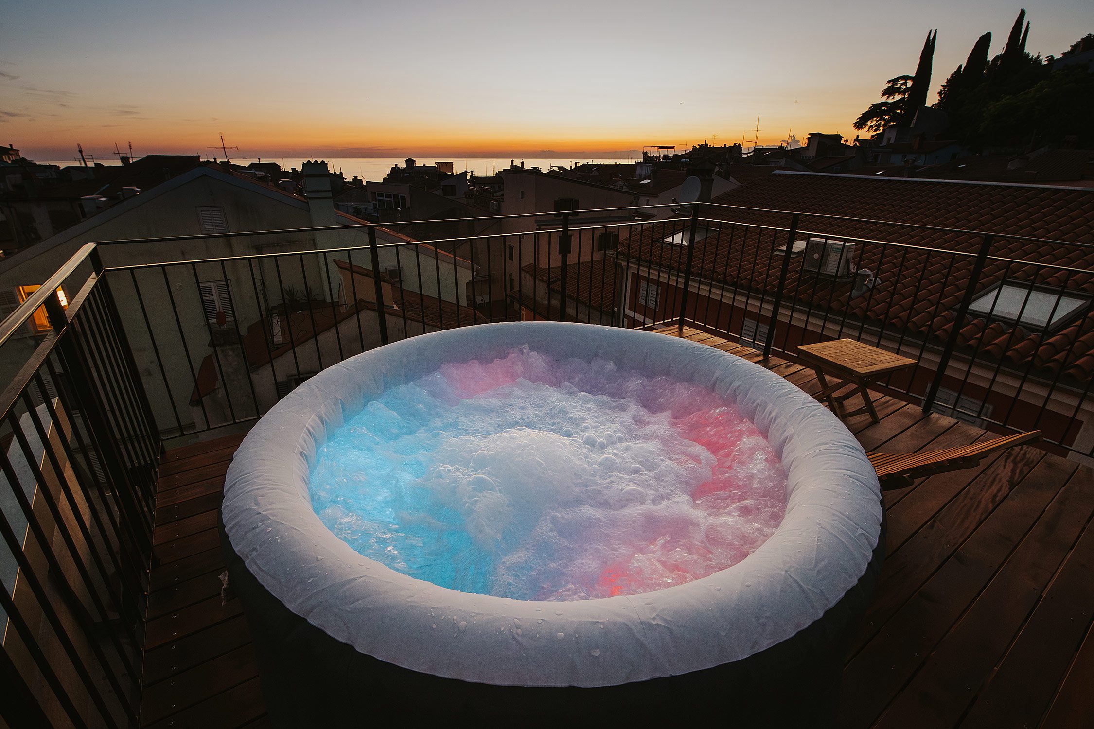 Zunanji jacuzzi na terasi ob barvitem sončnem zahodu nad Piranom